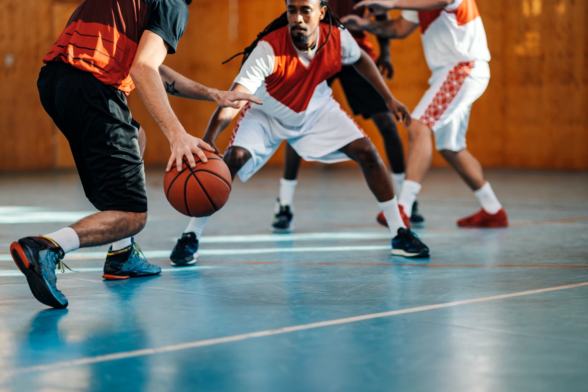Basketball player driving with the ball against a defender on an indoor court